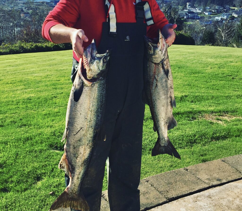 A fisherman holding up two Chinook salmon