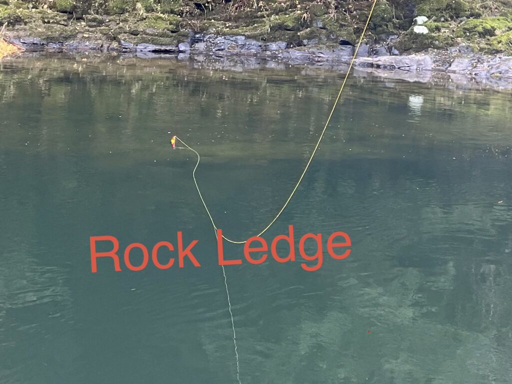 Salmon float fishing near a rock ledge showing how bait drifts along structure instead of staying strictly on the bottom
